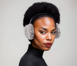Woman wearing faux fur earmuffs in gray and white.