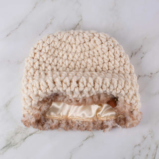 Cream satin lined winter hat with a brown and white faux trim.