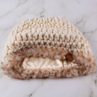 Cream satin lined winter hat with a brown and white faux trim.