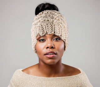 Woman wearing a beige satin lined ponytail beanie. Messy bun hat.