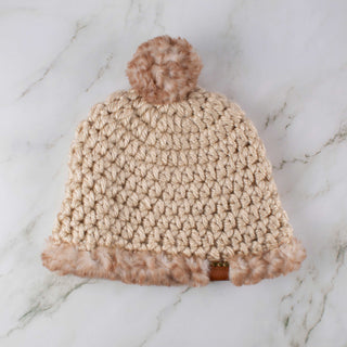 Beige satin lined winter hat with a brown and white faux fur pom and trim.
