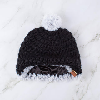 Black satin lined winter hat with a white faux fur pom and faux fur trim.