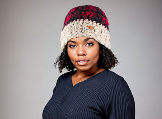 Woman with curly natural hair wearing a satin lined winter hat in red and black buffalo plaid.